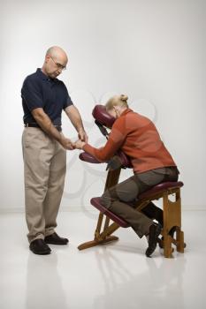 Royalty Free Photo of a Massage Therapist Massaging the Hands of a Woman Sitting in a Massage Chair