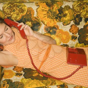 Royalty Free Photo of a Woman Lying on a Retro Sofa Talking on a Telephone