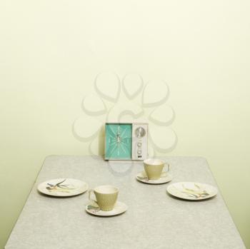 Royalty Free Photo of a Retro 50's Table Setting With Dishes, Coffee Cups and Vintage Clock Radio