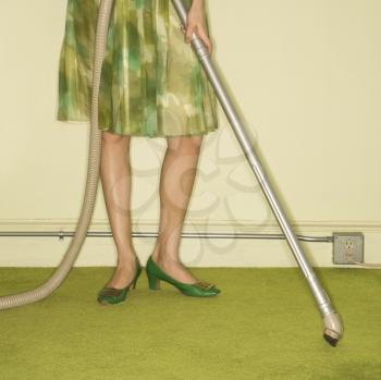 Royalty Free Photo of a Close-Up of a Woman's Feet With a Vacuum Against a Green Retro Carpet