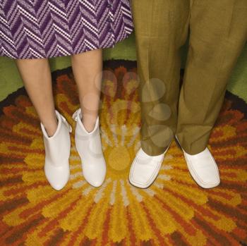 Royalty Free Photo of a Man and Woman's Legs Against a Sunburst Rug