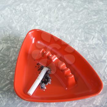 Royalty Free Photo of a Red Vintage Ashtray Containing a Cigarette Butt and Ashes