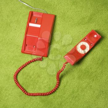 Red vintage rotary telephone on 70's green carpet.