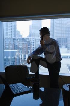 Royalty Free Photo of a Middle-aged Male in an Office on the Phone With the Skyline in the Background
