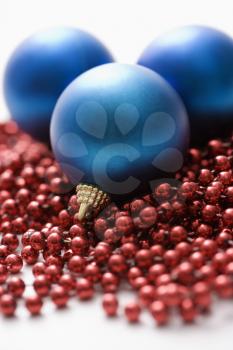 Royalty Free Photo of Blue Christmas Ornaments and Strings of Red Beads