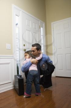 Royalty Free Photo of a Businessman at Door with Briefcase Hugging His Daughter