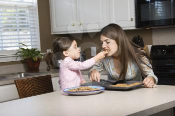 Royalty Free Photo of a Girl Feeding Her Mother Cookies