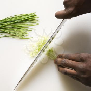 Royalty Free Photo of Male Hands Using a Large Kitchen Knife to Chop Fresh Chives
