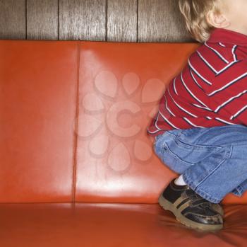 Royalty Free Photo of a Boy Kneeling on a Vinyl Sofa