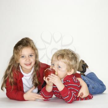 Royalty Free Photo of a Girl With Her Arm Around a Boy Eating an Apple