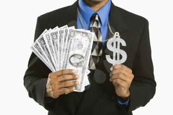Royalty Free Photo of an African American Man in a Suit Wearing a Necklace With a Money Sign and Holding Cash