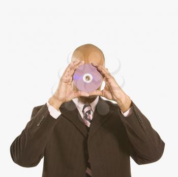 Royalty Free Photo of a Man Holding a Compact Disc Over His Face