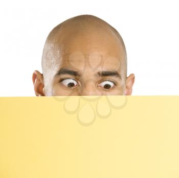 Royalty Free Photo of a Man Peeking Over a Blank Yellow Sign