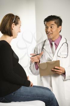Royalty Free Photo of a Male Doctor Examining a Pregnant Female Patient