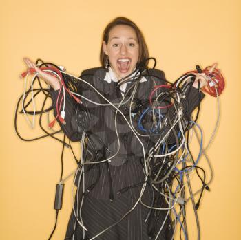 Caucasian businesswoman smiling holding pile of tangled cords and wires.