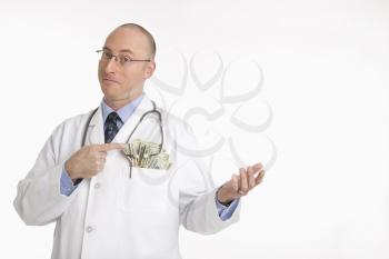 Royalty Free Photo of a Doctor Pointing to a Pocketful of Cash
