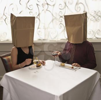 Royalty Free Photo of a Couple Dining in a Restaurant With Paper Bags Over Their Heads
