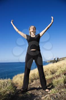 Royalty Free Photo of a Woman Standing on the Rocky Coast of Maui, Hawaii With Arms Outstretched
