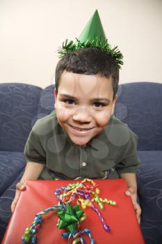 Royalty Free Photo of a Boy Wearing a Party Hat Holding a Large Birthday Present and Smiling