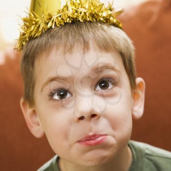 Royalty Free Photo of a Boy Wearing a Party Hat Making a Facial Expression 