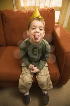 Royalty Free Photo of a Boy With a Party Hat Sticking Out His Tongue