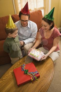 Royalty Free Photo of a Boy in a Party Hat Looking at His Birthday Cake