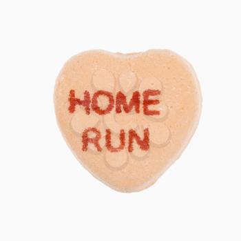Orange candy heart that reads home run against white background.