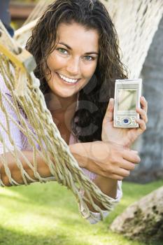 Royalty Free Photo of a Smiling Pretty Woman Lying in a Hammock Holding a PDA
