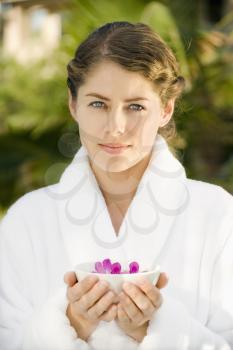 Royalty Free Photo of a Woman in a White Robe Holding a Bowl of Purple Orchids Floating in Water