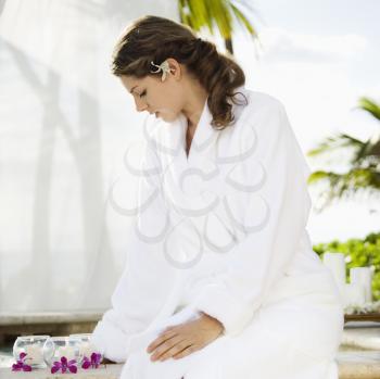 Royalty Free Photo of a Woman at a Spa Wearing a Robe Looking Down at Candles and Orchids
