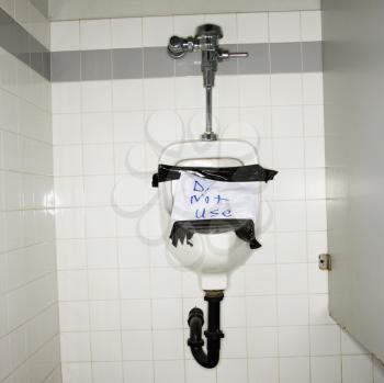 Royalty Free Photo of a Urinal in the Males Bathroom With an Out of Order Sign Taped On It