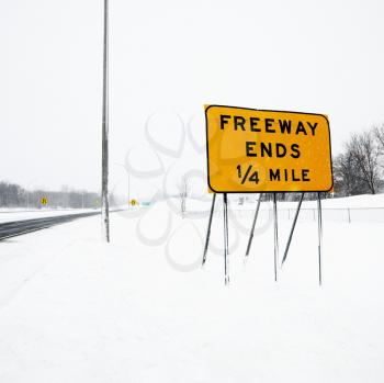 Royalty Free Photo of a Snow Covered Highway With a Sign Reading Freeway Ends Quarter Mile