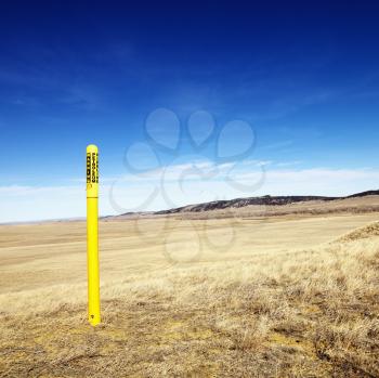 Royalty Free Photo of a Yellow Petroleum Warning Pole in a Scenic Landscape