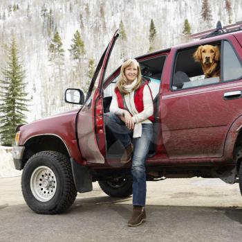 Royalty Free Photo of a Woman Sitting in a Dirty SUV with a Dog in the Back Seat