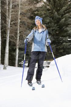 Royalty Free Photo of a Female Skier Wearing Blue Ski Clothing Standing on a Ski Slope Smiling