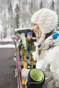 Royalty Free Photo of a Couple Unloading Ski Equipment From a Vehicle Smiling and Laughing