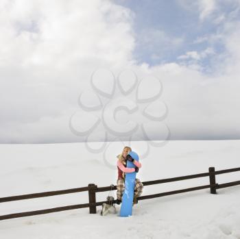 Royalty Free Photo of a Woman Holding a Snowboard and Sitting on a Fence