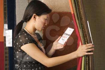 Royalty Free Photo of a Woman Shopping for Rugs in a Retail Store