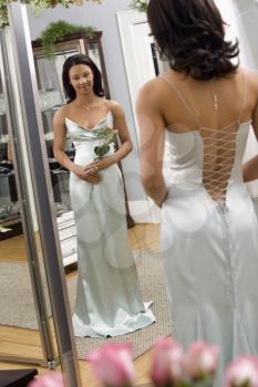 Royalty Free Photo of an Attractive Woman Wearing an Evening Gown Looking in the Mirror While Holding Flowers