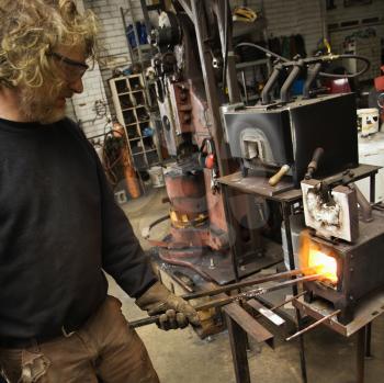 Royalty Free Photo of a Metal Smith Heating Metal in a Forge