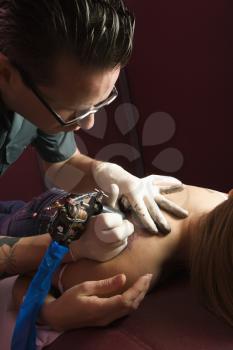 Royalty Free Photo of a Male Tattoo Artist Tattooing a Woman