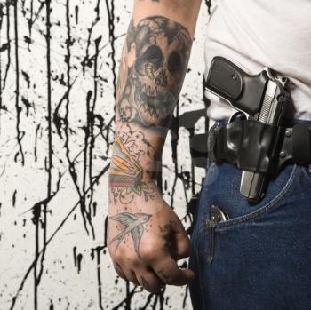 Royalty Free Photo of a Tattooed Man Wearing a Holster With a Gun