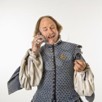Royalty Free Photo of William Shakespeare in Period Clothing Talking on a Cellphone and Laughing