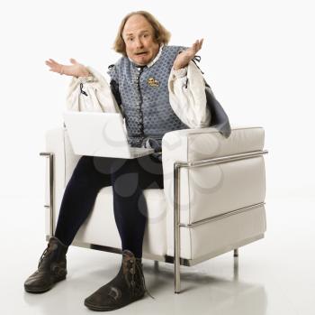 Royalty Free Photo of William Shakespeare in Period Clothing Sitting With a Laptop