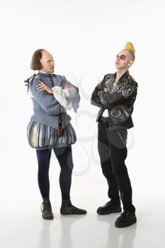 Royalty Free Photo of William Shakespeare in period clothing and gothic punk young man standing face to face with arms crossed