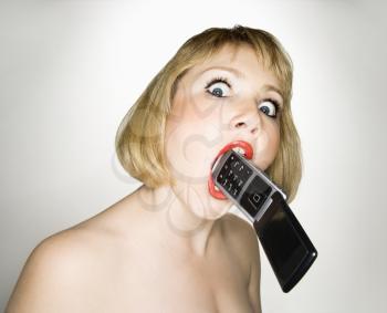 Royalty Free Photo of a Blonde Caucasian Woman Who Has a Cellphone in Her Mouth