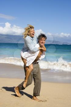 Royalty Free Photo of a Man Giving a Woman a Piggyback on the Beach in Maui, Hawaii