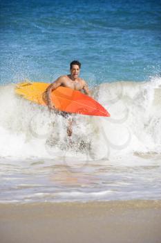 Royalty Free Photo of a Young Man Running Out of Water Carrying a Surfboard in Maui, Hawaii