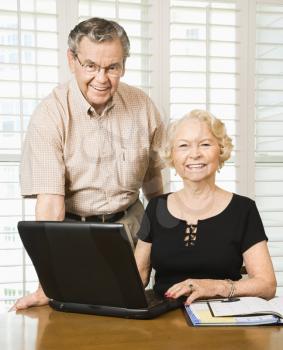 Royalty Free Photo of an Older Couple Looking at Their Calendar and Using a Laptop