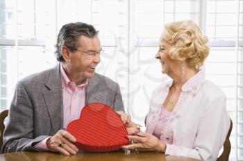 Royalty Free Photo of an Older Man Giving a Valentine's Heart Box to an Older Woman